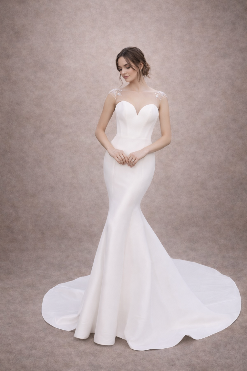 A woman in a elegant, fitted white wedding dress with a sweetheart neckline and a train, standing gracefully against a neutral background.