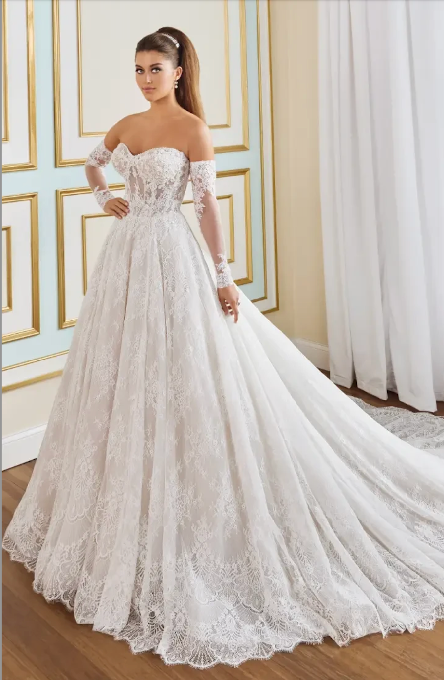 model is wearing an off the shoulder lace ball gown wedding dress